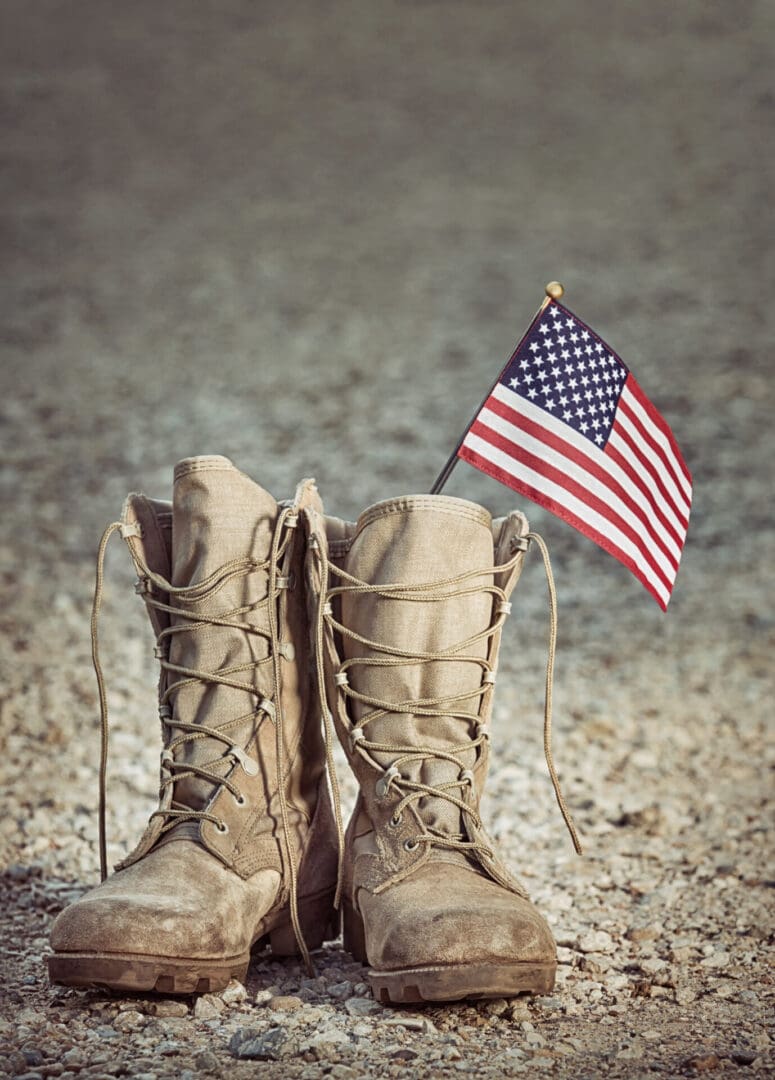 Old,Military,Combat,Boots,With,The,American,Flag.,Rocky,Gravel